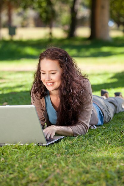 Vrouw die aan haar laptop in het park werkt