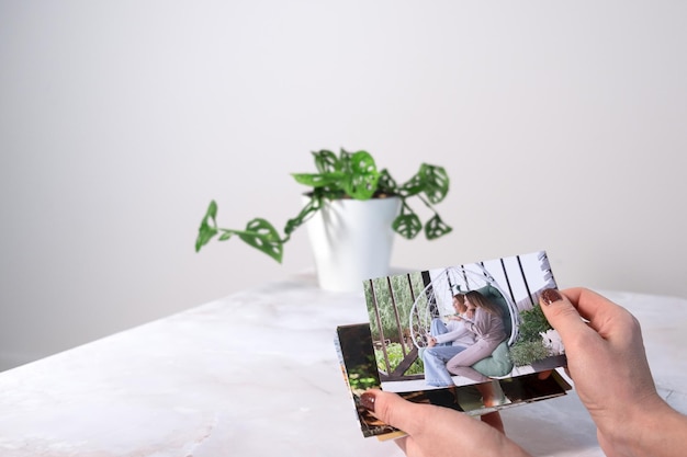 Vrouw die aan het bureau zit en naar afgedrukte foto's kijkt, herinnert zich nostalgie naar een rustdag fotografiekaarten achtergrond Mock up