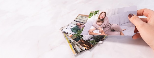 Vrouw die aan het bureau zit en naar afgedrukte foto's kijkt, herinnert zich nostalgie naar een rustdag fotografiekaarten achtergrond mock up