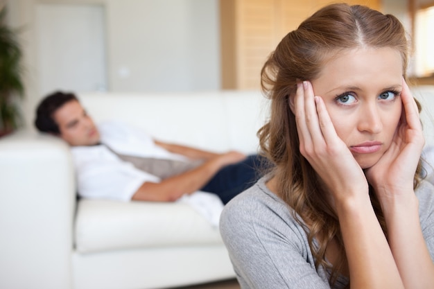 Vrouw die aan hoofdpijn met de mens op de bank achter haar lijdt