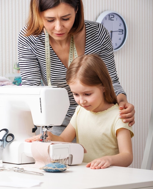 Vrouw die aan kind toont hoe thuis te naaien