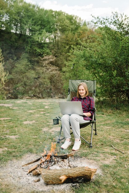 Vrouw die aan laptop online op aard werkt. jonge freelancer ontspannen in het bos