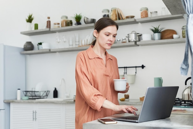 Vrouw die aan laptop thuis werkt.