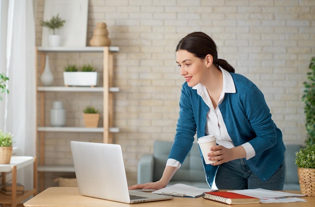 Vrouw die aan laptop thuis werkt.