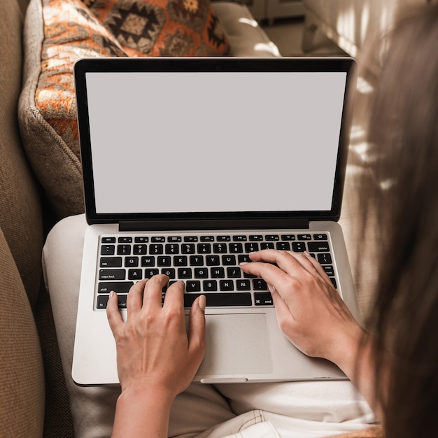 Vrouw die aan laptop werkt die op de bank ligt