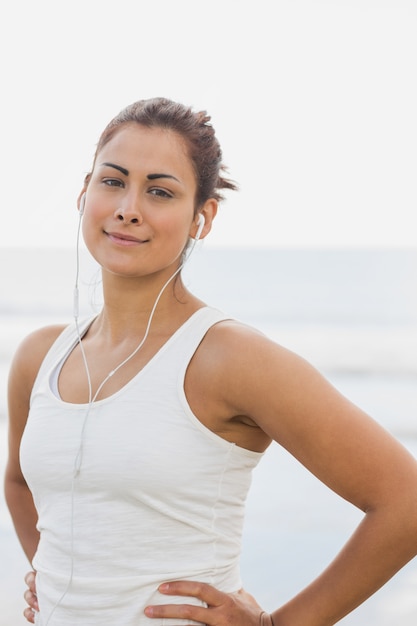 Vrouw die aan muziek door oortelefoons bij strand luistert