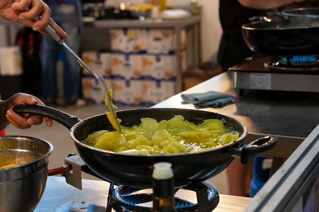 Vrouw die aardappelen bakt om een typisch gerecht genaamd tortilla de patatas van de Spaanse gastronomie te koken