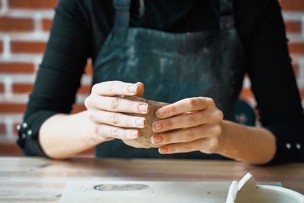 Vrouw die aardewerk, handenclose-up maken, vaag, nadruk op pottenbakkers, palmen met aardewerk