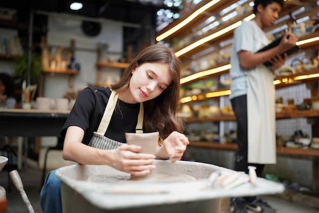 Vrouw die aardewerk maakt in workshop Natte klei vormen op aardewerkwiel