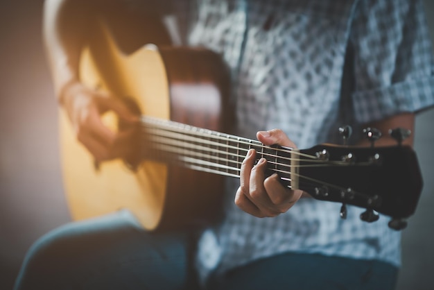 Vrouw die akoestische gitaar speelt zittend in een openbaar park in een ontspannen vrouw die gelukkig gitaar speelt onder een boom