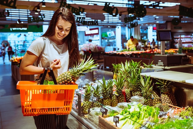 Vrouw die ananas kiest in de supermarkt