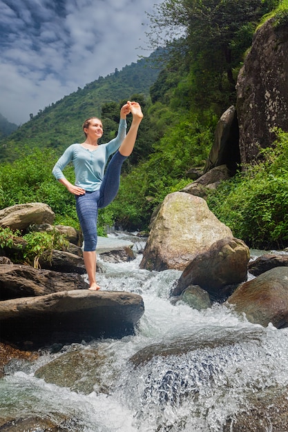 Vrouw die Ashtanga Vinyasa Yoga-asana in openlucht doet bij waterval