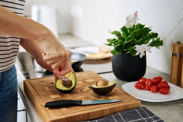 Vrouw die avocado snijdt op snijplank om ontbijt te bereiden