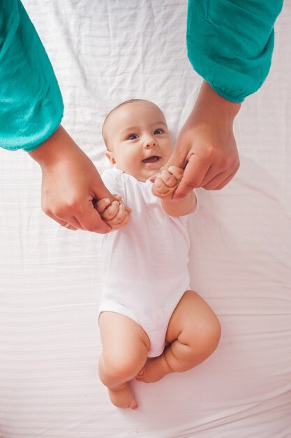 Vrouw die babyhanden masseert, schattige jongen lacht