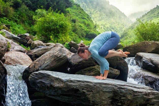 Vrouw die Bakasana asana buitenshuis doet