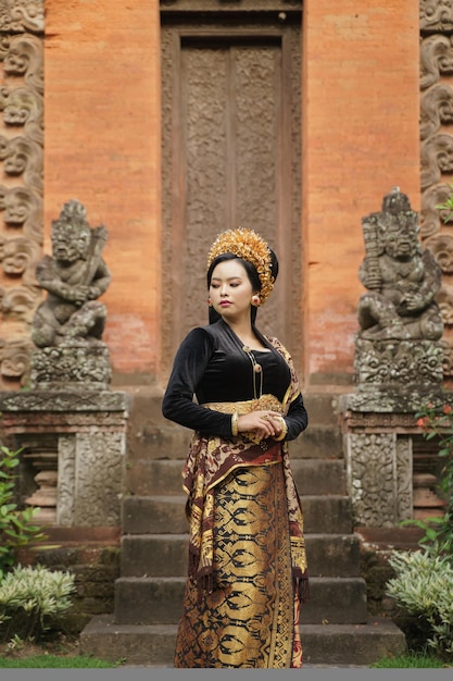 Vrouw die balinese kebaya draagt die kant tegen tempel kijkt