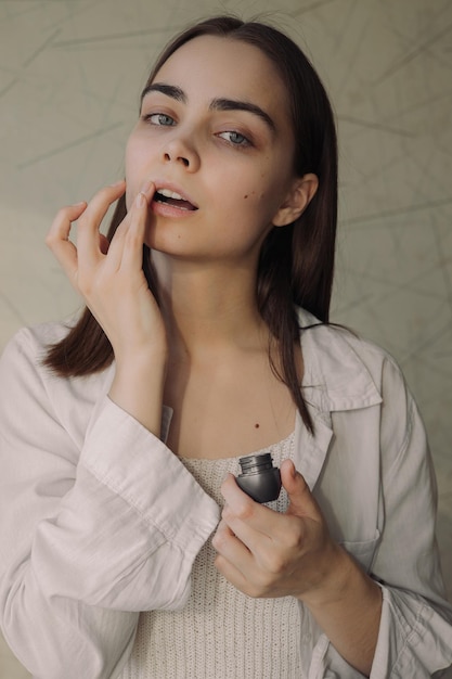 vrouw die beschermende lippenbalsem met vinger aanbrengt terwijl ze huidverzorging schoonheidsroutine doet