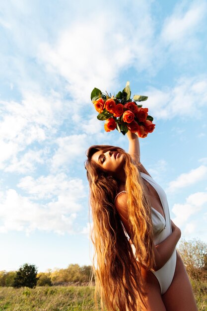 Foto vrouw die bij een bloeiende plant tegen de lucht staat