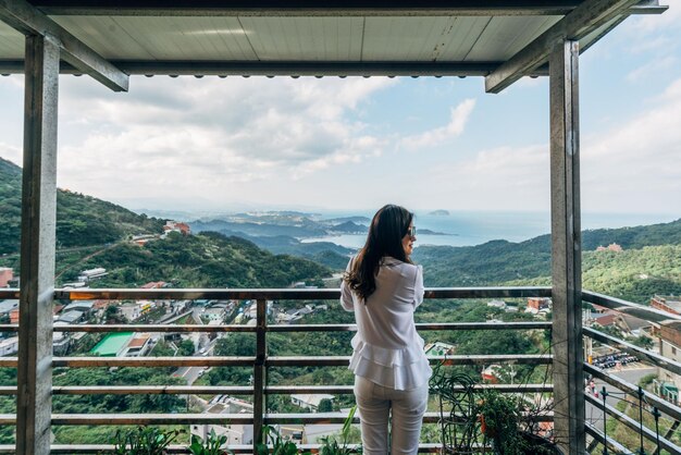 Foto vrouw die bij een reling tegen de bergen staat