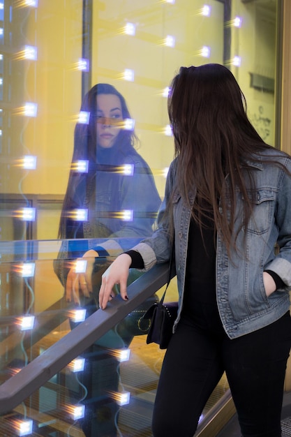 Foto vrouw die bij een verlichte muur staat