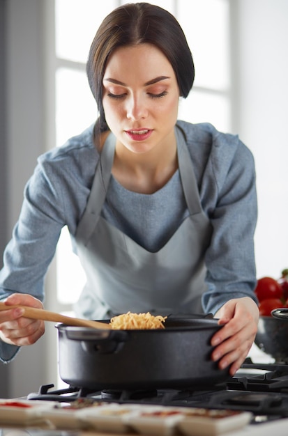 Vrouw die bij het fornuis in de keuken staat te koken en de lekkere aroma's ruikt