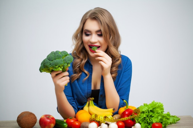 Vrouw die bij lijst een broccoli van groenten en fruit houdt