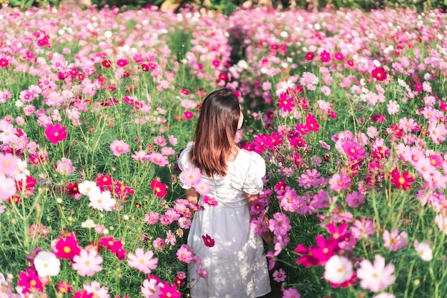 Vrouw die bij roze bloeiende planten staat