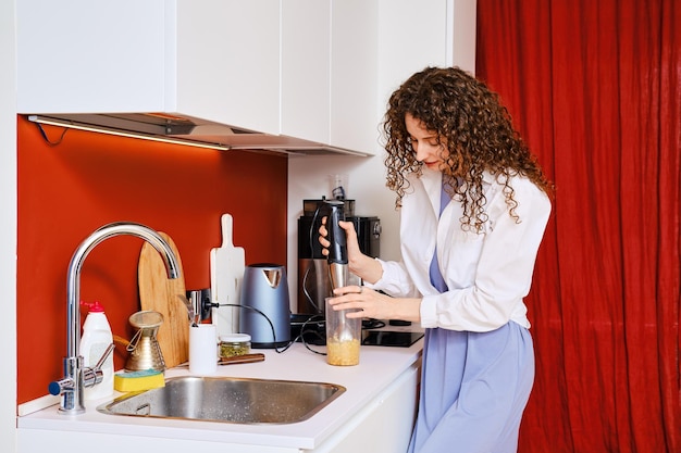 Vrouw die blender gebruikt om thuis hummus te maken