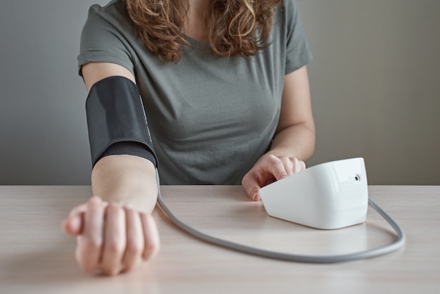 Vrouw die bloeddruk zelf meten met digitale manometer. gezondheidszorg en medisch concept