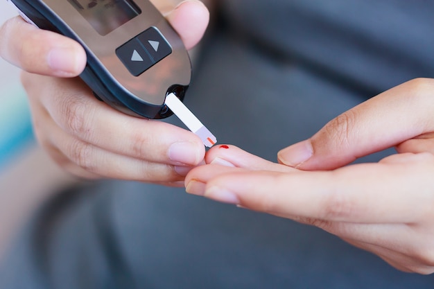 Foto vrouw die bloedsuikerspiegel controleert met glucometer