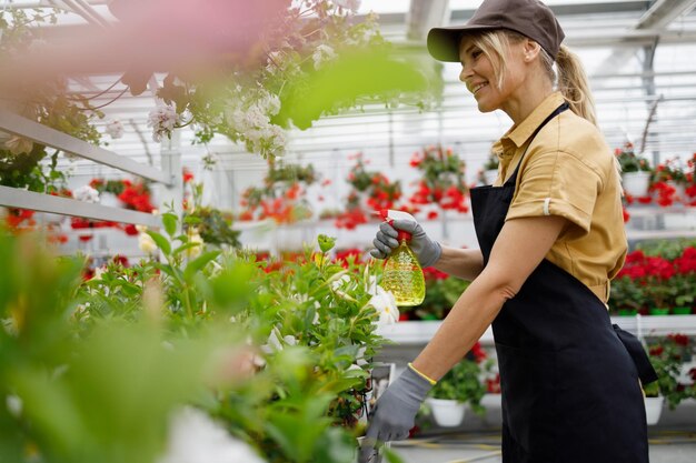 Vrouw die bloemen in de tuin spuit