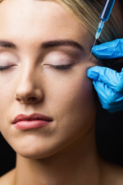 Vrouw die botox injectie op haar voorhoofd ontvangt