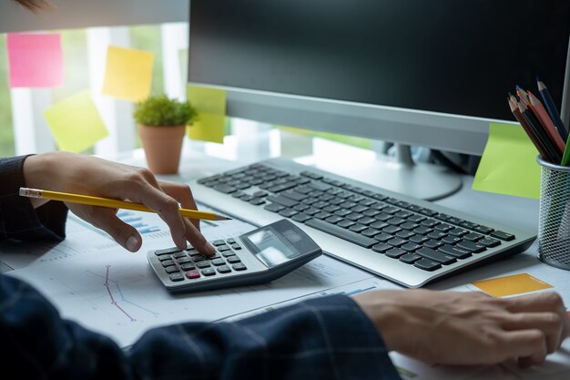 Vrouw die calculator gebruikt terwijl het werken voor financiële documenten