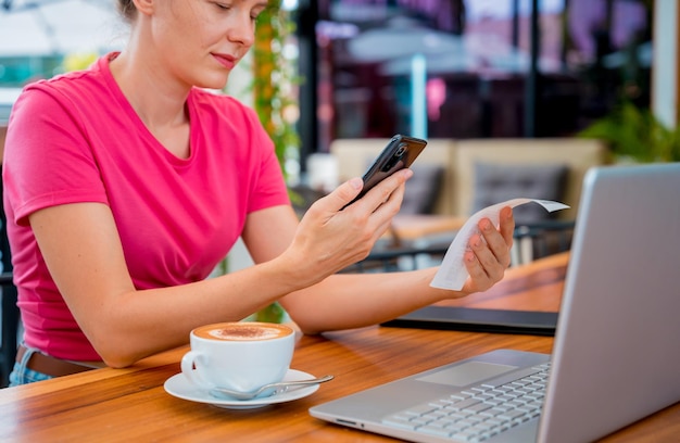 Vrouw die contactloos betalen via mobiele telefoon met qr-code in café