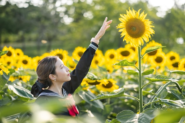 Vrouw die cosplay japans schooluniform draagt bij zonnebloemtuin buiten