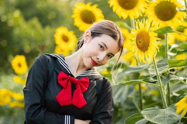 Vrouw die cosplay Japans schooluniform draagt bij zonnebloemtuin buiten