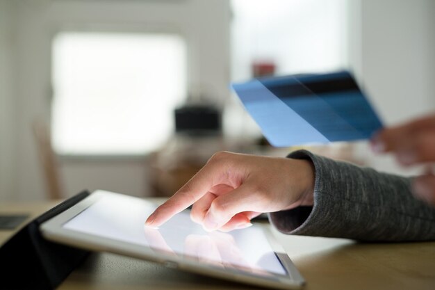 Foto vrouw die creditcard gebruikt om op tablet te betalen