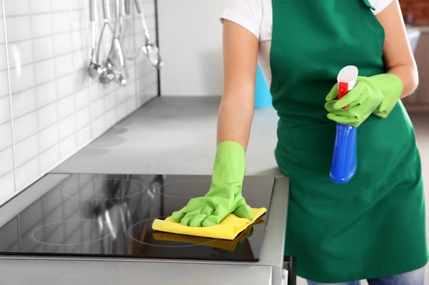 Vrouw die de kachel in de keuken schoonmaakt