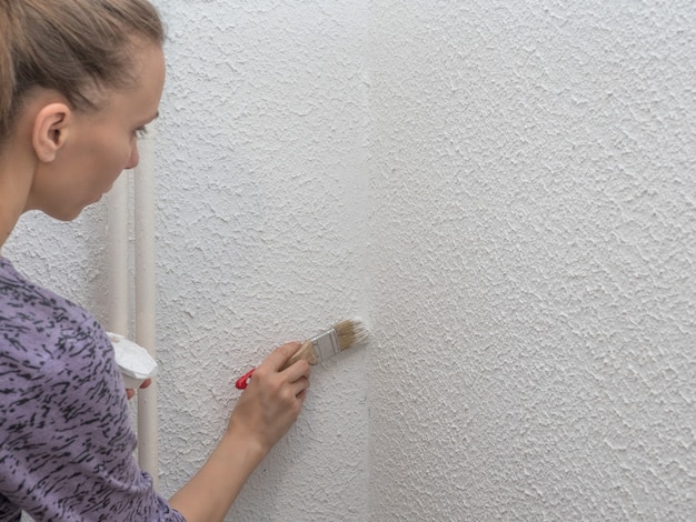 Vrouw die de muur schildert. Restauratie van de geschilderde witte muren.