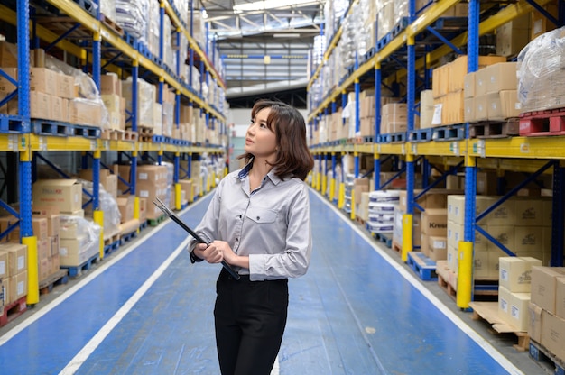 Vrouw die de producten in de plank bij de grote opslag en het magazijn controleert en telt