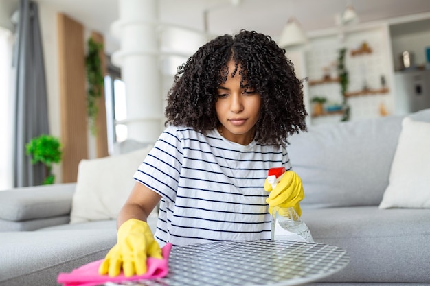 Vrouw die de tafel schoonmaakt en polijst met een schoonmaak- en hygiëneconcept voor spraywasmiddel