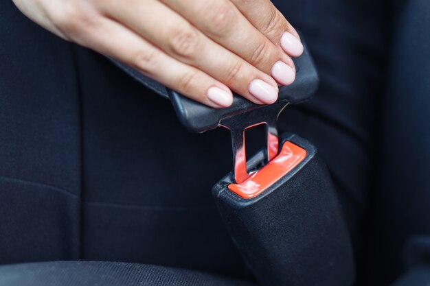 Vrouw die de veiligheidsgordel in een auto gebruiken