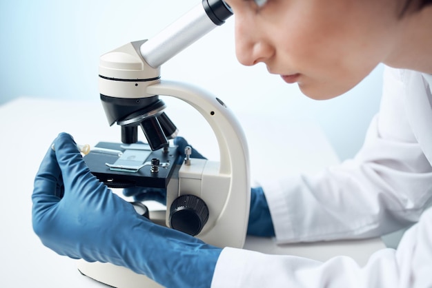 Vrouw die door een close-up van het wetenschapsonderzoek van de microscoopdiagnostiek kijkt