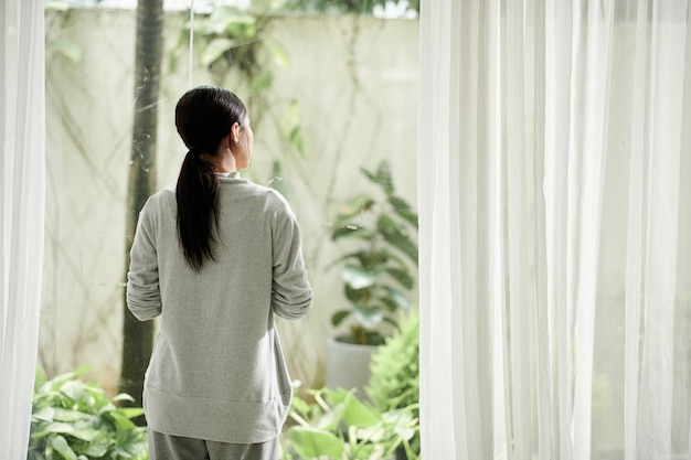 Vrouw die door groot raam kijkt