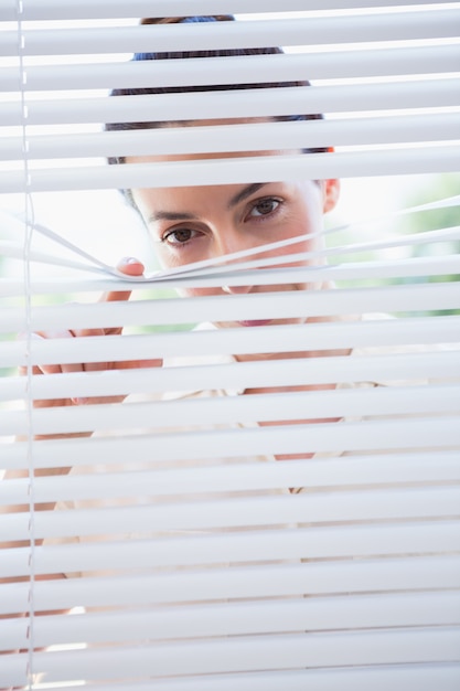 Vrouw die door zonneblinden gluren