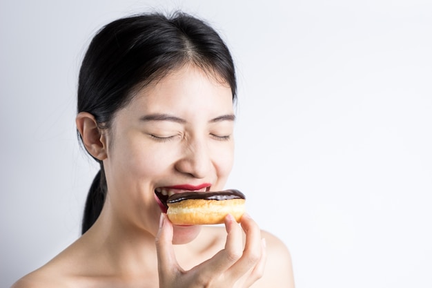 Vrouw die doughnut op witte achtergrond eet