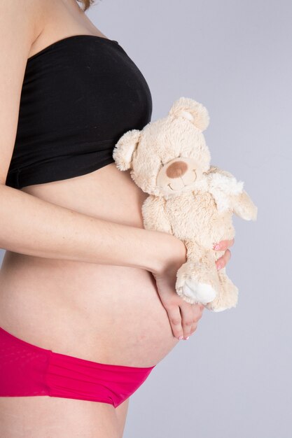 Vrouw die een baby met een leuke teddybeer verwacht