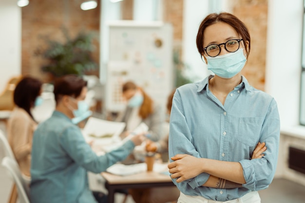 Vrouw die een beschermend masker draagt terwijl ze op kantoor werkt