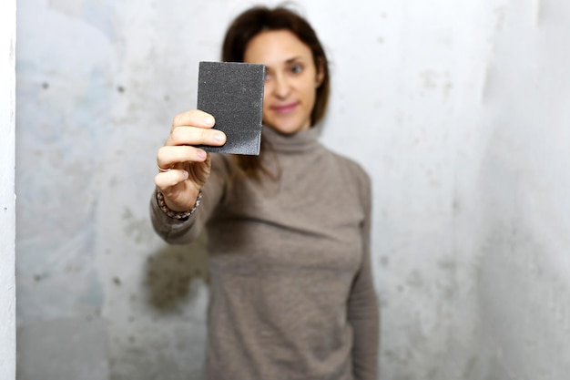 Foto vrouw die een blok schuurpapier laat zien op het werk thuis concepthervorming in het schilderen of behangen van huis