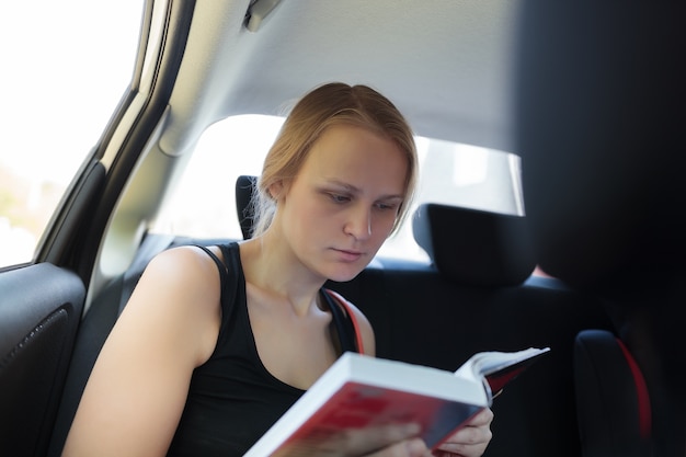 Vrouw die een boek in de auto leest